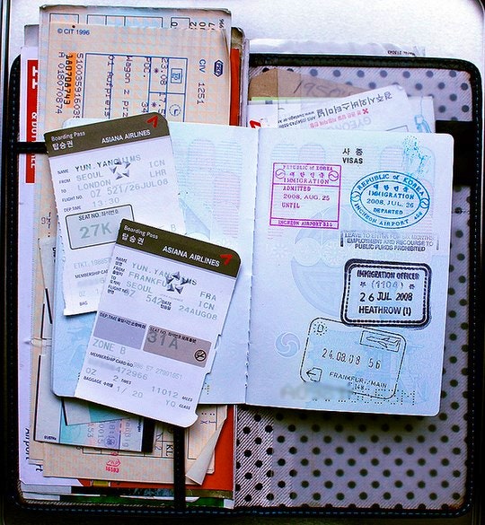 Wallet, passport, flight information in a travel wallet. By Georgina from the past (Flickr)