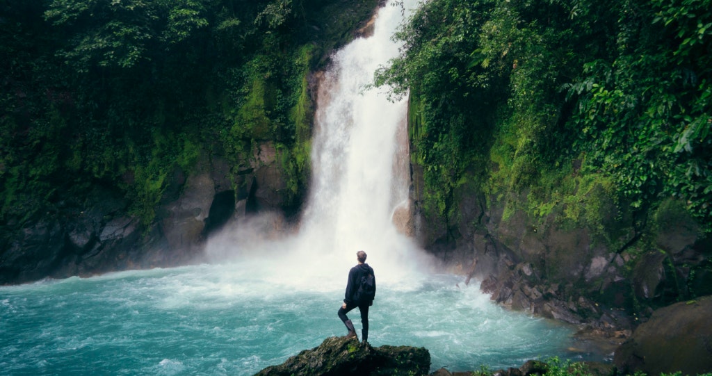 Man in front of Waterfall Safe Travel